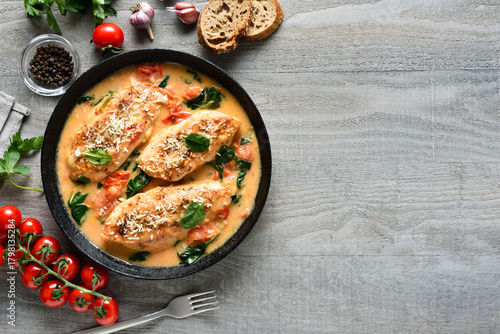 Chicken breast in creamy sauce with tomatoes and spinach on plate