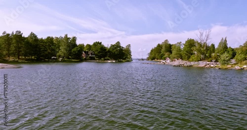 Landscape view of Nokasundet strait from moving passenger ferry in summer weather with clouds in the sky, Pirttisaari, Porvoo, Finland. 