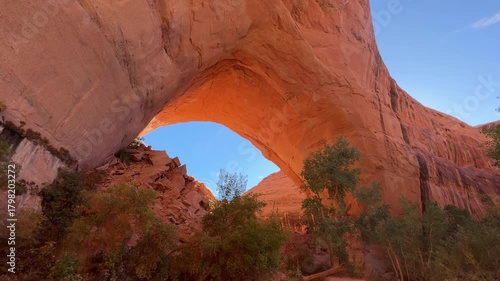 Sunlight pouring through Jacob Hamblin Arch with blue sky and streaked clouds