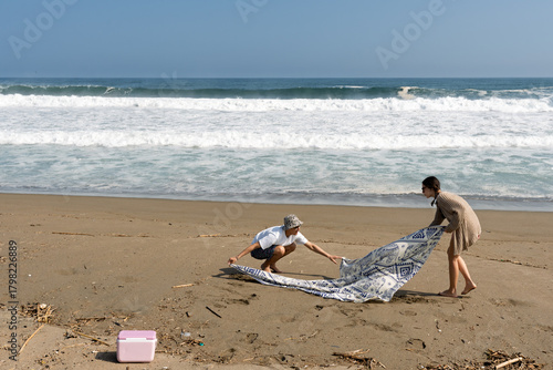 Young couple laying blanket on beach for relaxation
