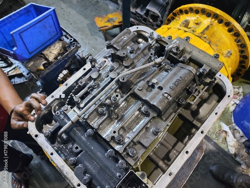 Overhead view of a disassembled hydraulic control valve body covered in oil and grime, a critical component of a heavy equipment automatic transmission or power shift gearbox