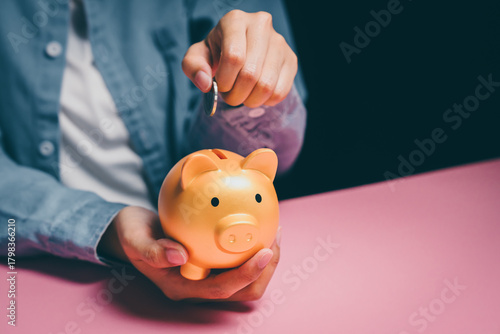Obraz na plátně Hand dropping coin into golden piggy bank, savings discipline, financial plannin