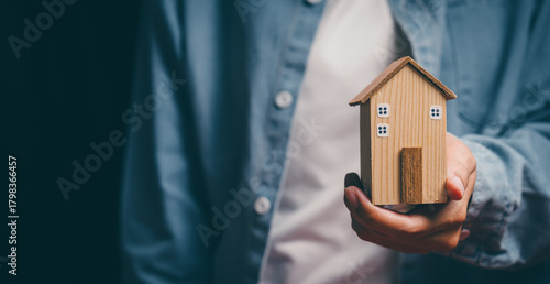 Hand holding wooden house, home security awareness, property protection stability, financial planning support, housing responsibility insight, reassurance and safe home value concept
