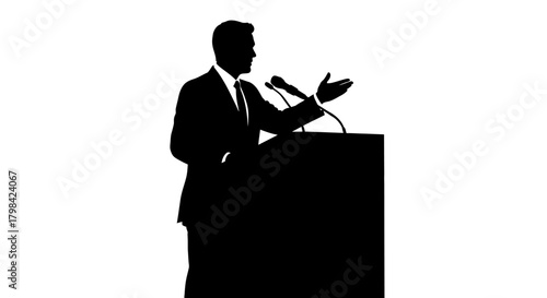 Man in suit speaking at podium with microphones, silhouetted