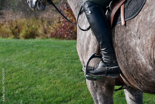 Closeup view of a horse rider’s boot resting in the stirrup while mounted on the horse