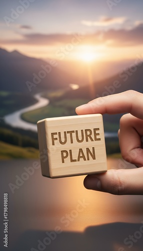Hand holding a wooden cube with FUTURE PLAN text, set against a scenic sunset landscape with a winding river, symbolizing strategic foresight and planning for the future.