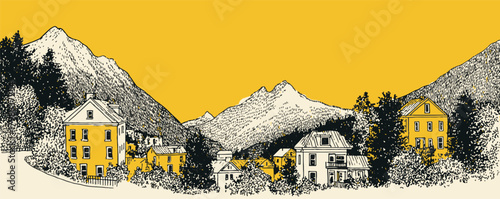 A mountain range with houses in the valley below. The houses are yellow and brown. The sky is orange and the mountains are covered in snow