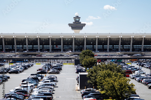 View of Washington Dulles airport terminal and parking lot under clear sky on a sunny day. g.