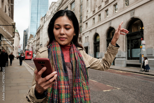 Canvas Print Woman using smartphone hailing ride on london street