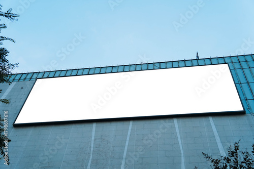 A mockup of a blank white billboard framed by a modern building facade, ideal for advertising