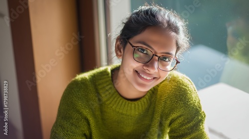 Smiling Indian Woman in Green Sweater by Window