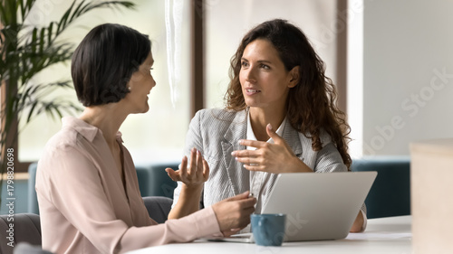 Photos Smart businesswoman explain task to female coworker by notebook screen