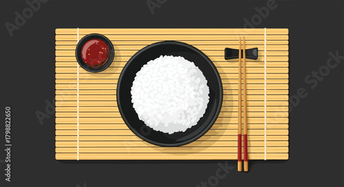 Overhead view of a traditional Asian meal featuring a black bowl of white rice, a dish of red sauce, and chopsticks on a bamboo placemat.