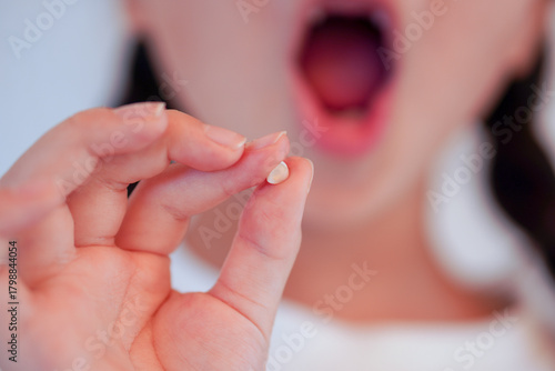 歯が抜けた！初めての乳歯を見せる女の子のクローズアップ