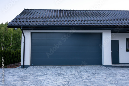 Designer entrance gate to a garage. Modern design. Luxurious exterior. Facade of a modern garage with modern gate. Gate to garage.