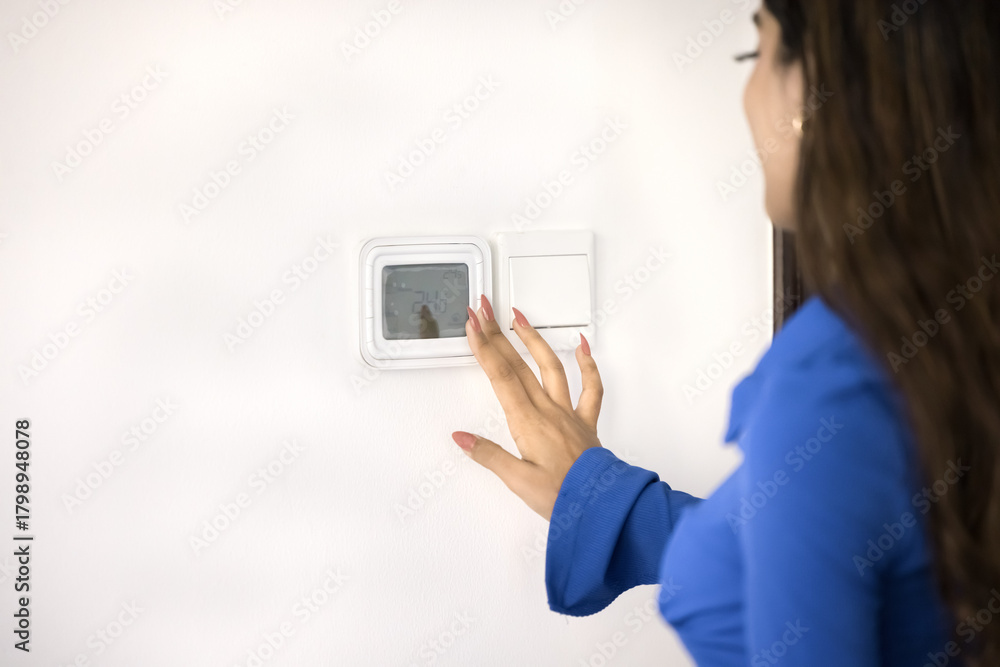 Fototapeta premium Young Indian woman using control panel for starting air conditioner