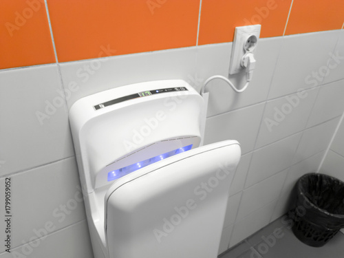 Air hand dryer on the wall of a public restroom WC