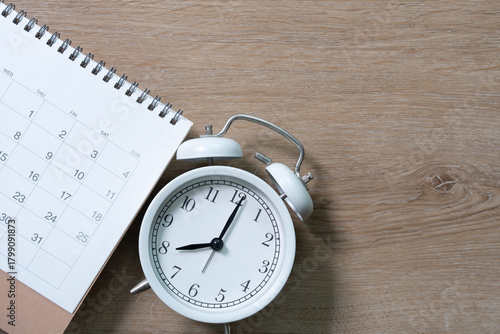close up of calendar and alarm clock on the wooden table background, planning for business meeting or travel planning concept