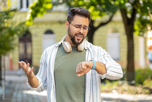 Quadro su tela Serious dissatisfied Caucasian man tourist in glasses standing outdoors looking
