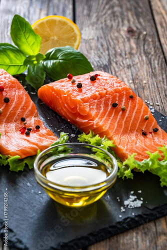 Fresh raw salmon steaks on black stony board on wooden background