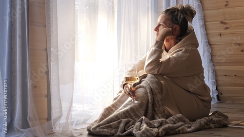 Canvas Print Woman with wine sitting near window surrounded by warm glow and gentle reflectio