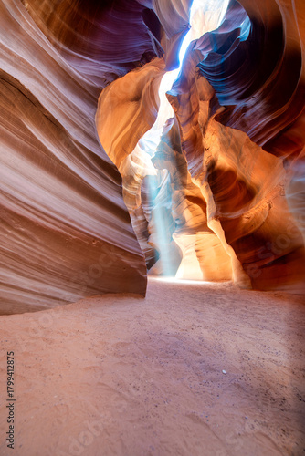 Spectacular Antelope Canyon interior with light beams illuminating red sand and sculpted rock walls