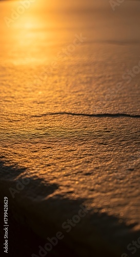 A serene sunset over the calm ocean surface, casting a warm golden glow and gentle ripples on the water during twilight