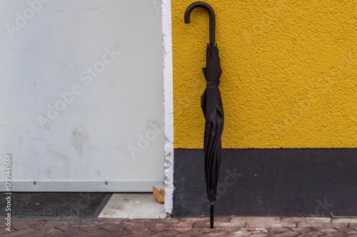 Black umbrella leaning against colorful urban wall