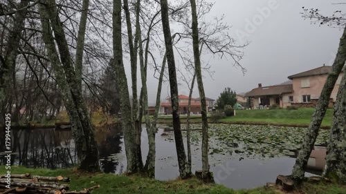A small tranquil lake in a traditional French Alpine village near Lyon during autumn. Colorful fall foliage surrounds the calm water, creating a peaceful mountain landscape.