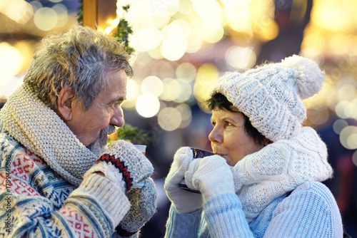 winter holidays, hot drinks and people concept - happy senior couple with coffee at christmas market in evening