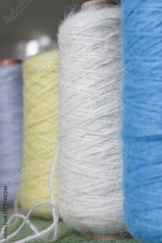Variety colours of alpaca wool and silk. Cones of multicoloured yarn. Wool threads in a row. Row of blue, white, yellow and grey wool. Knitting hobby. Bobbins of yarn. Bright wool for knitting. 