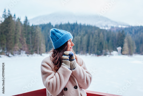 Fotografía Young woman tourist admiring snowy mountain Synevyr lake view wearing white warm fur coat