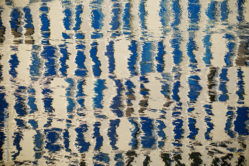 Abstract reflection of blue and white building façades distorted on rippling water