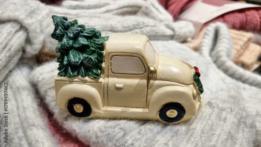 Delivery gift of a white Christmas car with a Christmas green tree, a toy for winter holidays on knitted warm blankets, thematic decor for children's parties, winter gift