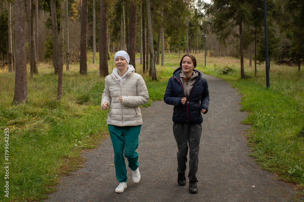 Fototapeta premium Cancer survivor running outdoors with companion, concept of motivation, endurance, and physical rehabilitation after chemotherapy.