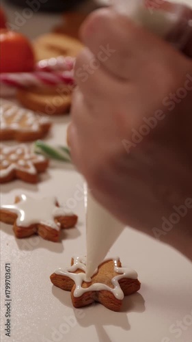 Watch as someone decorates delicious homemade gingerbread star cookies with white icing. Perfect for a festive Christmas treat or holiday baking activity.