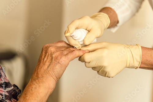 A home care nurse provides wound care to an elderly woman’s finger during an in-home medical visit.