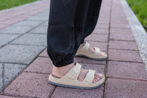 Schilderij op canvas Close up of person wearing beige sandals on walkway