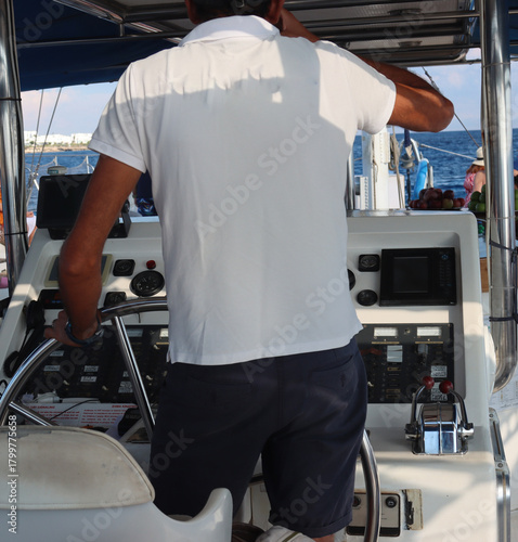 Sailor steering yacht on calm blue sea