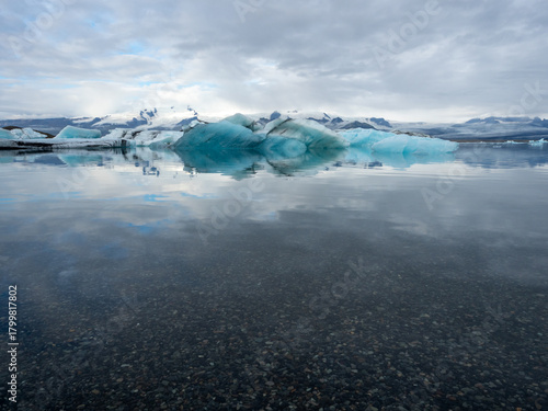 Clear water of Iceland's Jokulsarlon Glacier Lagoon with icebergs floating in the background