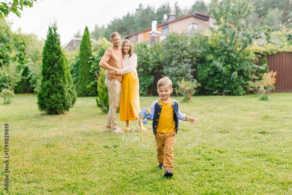 Obraz premium Happy Child Running With Bubble Gun Outdoors