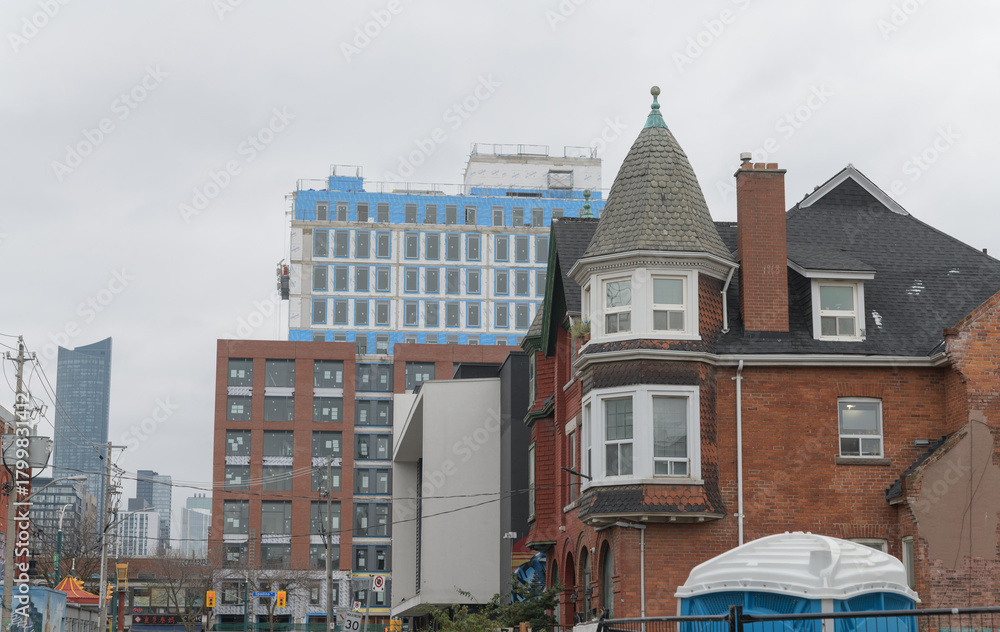 Fototapeta premium contrast of architectural styles: historic house on St Andrew St near Spadina Av and beyond residential buildings and a skyscraper condo in Toronto