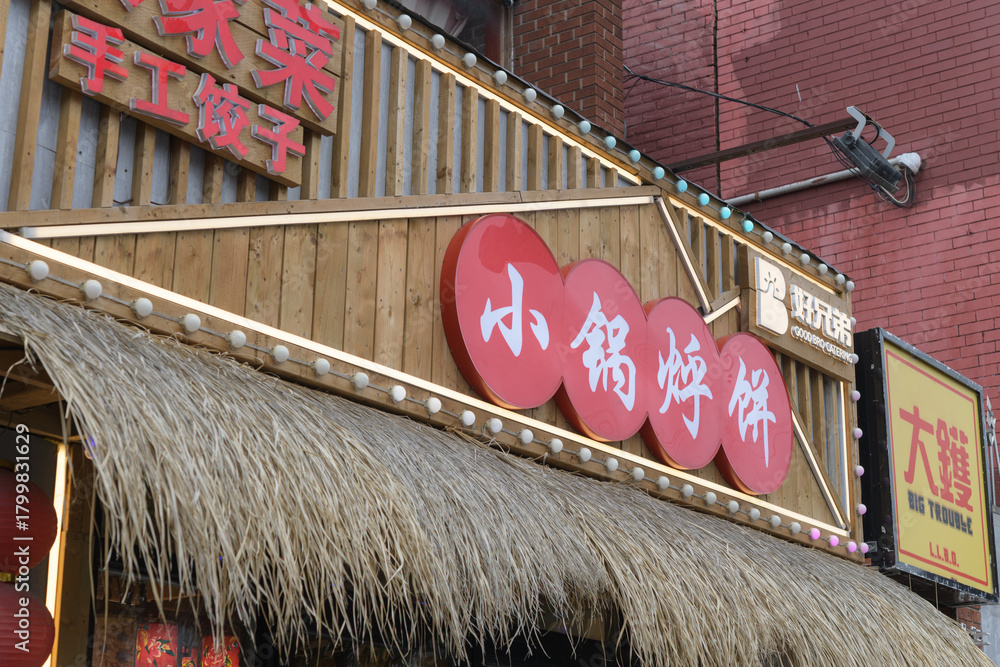Fototapeta premium exterior of a restaurant, 好兄弟小锅烀饼 (XiaoGuoHuBing), located at 460 Dundas St W in Chinatown, Toronto - Big Trouble bar and cocktail lounge
