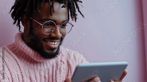 stylish african american man wearing glasses looking at a tablet with a smile
