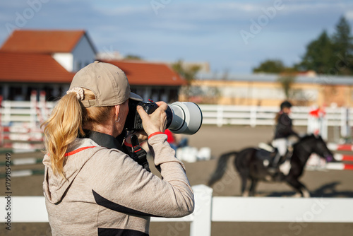 Sports photographer with camera and telephoto lens capturing equestrian show jumping. Photography themes