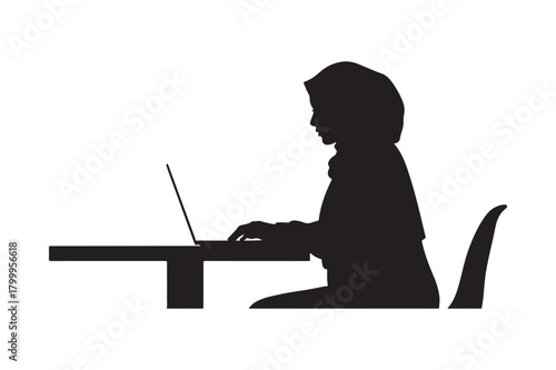 Silhouette of a person working on a laptop at a desk