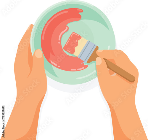 Hands holding a plate while dipping a brush into thick pink paint, preparing for artistic work