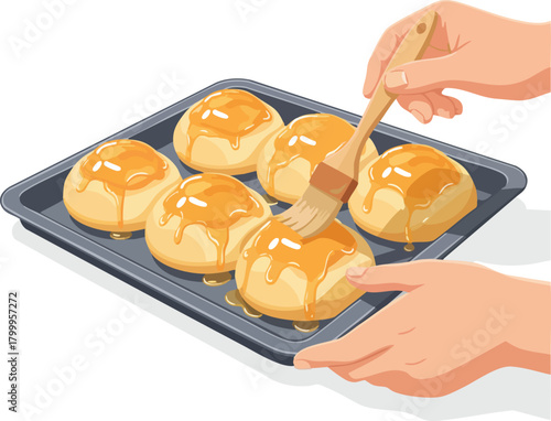 Hands brushing warm golden glaze over freshly baked buns resting on a tray straight from the oven
