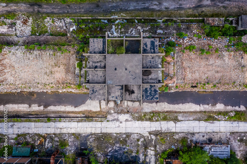 Top-down drone view of abandoned coal-era industrial complex with concrete ruins and overgrown brownfield