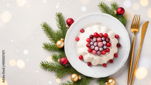 Christmas dessert with meringue and cranberries served on white plate with festive decorations, pine branches and golden cutlery. Holiday food concept